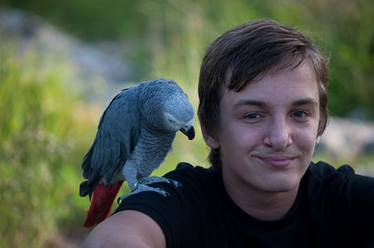 Portrait of a teenage boy with a gray parrot Jaco.