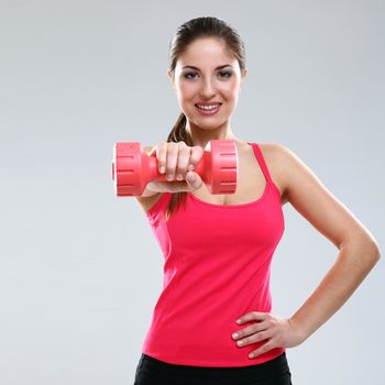 Young beautiful woman in fitness wear with dumbbells isolated over background