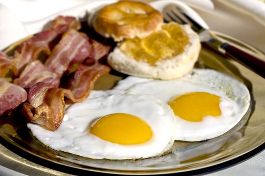 Breakfast plate outside with eggs, bacon, and biscuits with apple jelly.