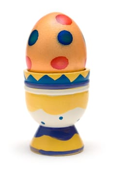 Colored egg in a wooden eggcup. Isolated on a white
background.