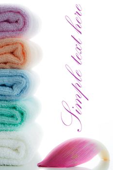 multicolor towels stacked with a lotus petal on white background and area for your text