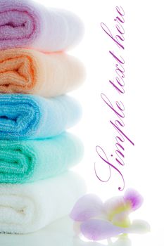 multicolor towels stacked with a orchid flower on white background and area for your text