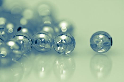 Desaturated clear beads on reflecting surface with mirror image for background use