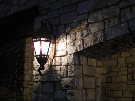 a lantern lit on a stone wall