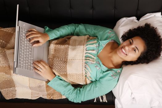 A young, brazilian woman surfing on the Internet with a Laptop.  
