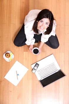 A young adult woman studying on the floor.