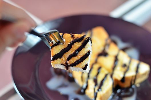 close up toast topped with sweetened condensed milk and chocolate sauce on fork