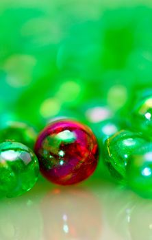 Red beads among the green smaller beads with mirror image in portrait orientation