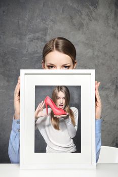 Girl holds a picture of a girl and red shoes