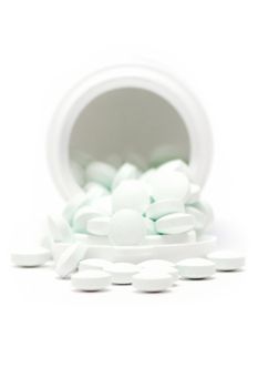 White tablets out of a plastic box. Isolated on a white background. Shallow depth of field.