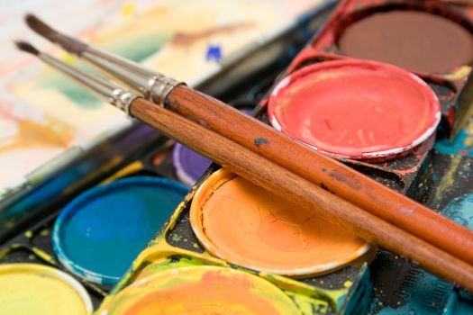 Detail shot on a box of watercolors and two paintbrushes.