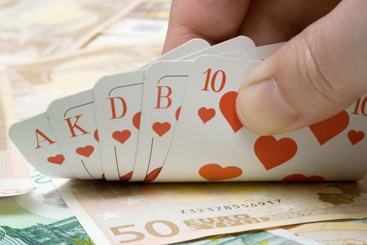 Revealing a royal flush on a money background.