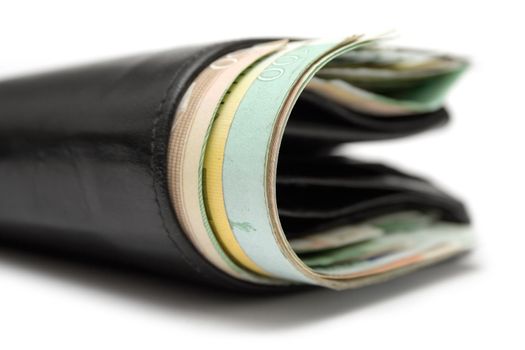 Close view on a black leather wallet full of banknotes. White background.