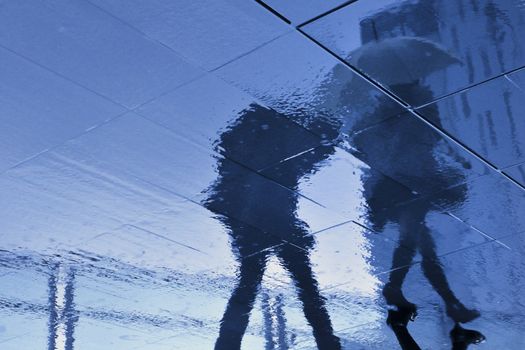 rainy pavement reflection of walking couple in Tokyo, Japan during rainy season which usually takes time in June