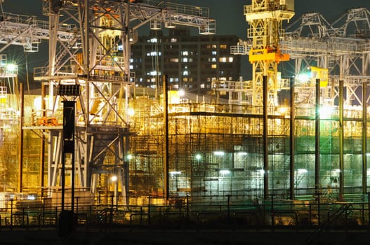 highly-detailed construction site well illuminated by night with huge metallic frames and cranes