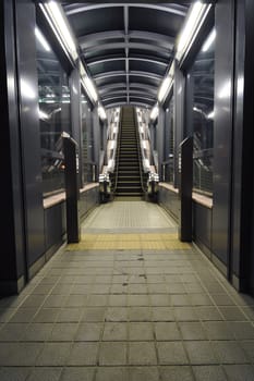 illuminated corridor between glass walls going to escalator entrance