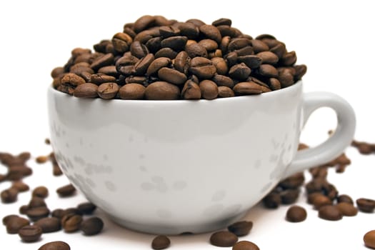 Big white cup full of brown coffee beans. Isolated on a white background.