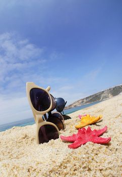 Holiday with friends � four pair of sunglasses on the beach and multicolor sea stars