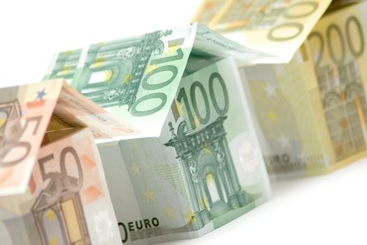 Close view on three colorful houses built of different euro bills. Isolated on a white background.