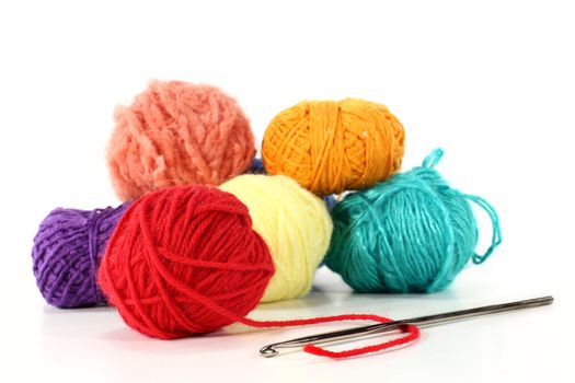 colorful balls of wool with crochet hook on a white background