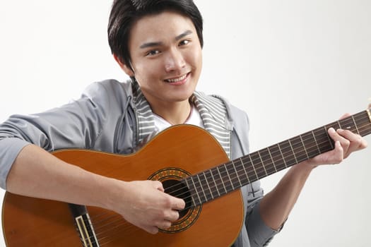 Young man playing guitar and looking at camera, portrait