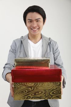 Young man carrying stack of gifts, smiling, portrait