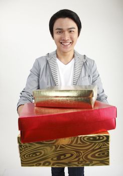 Young man carrying stack of gifts, smiling, portrait