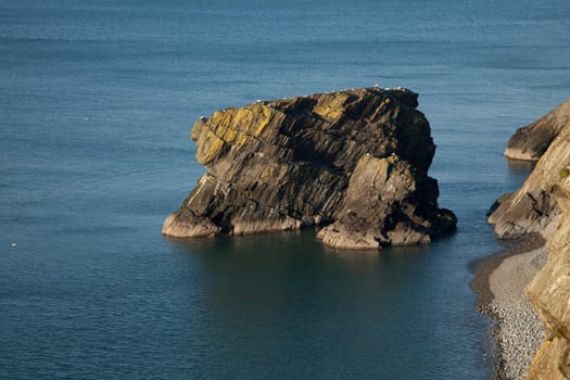 The sea stack Trwyn y Tal and a pebble shore, on the Wales coast path at Trefor, Lleyn peninsular, Wales, UK.