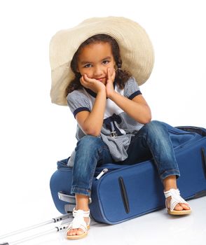 The young mulatto traveler girl with hat and a suitcase. Isolated over white background. Vertical view