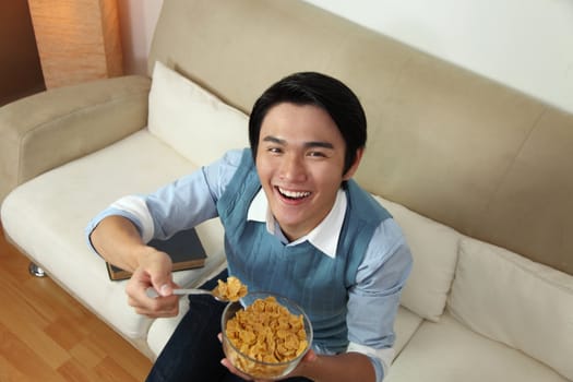 Smiling man eating a bowl of cereals