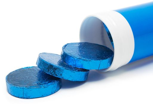 Pills in blue metallic wrapping paper isolated on a white background.