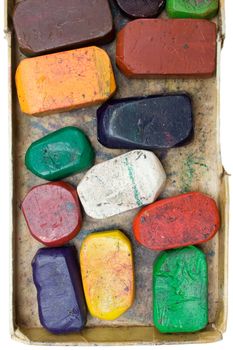 Colorful wax crayons in an old box. Isolated on a white background.