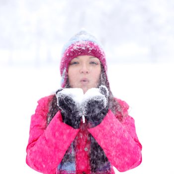 winter girl blow on snow in hands