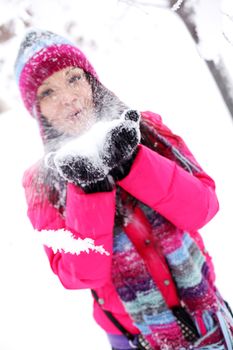 winter girl blow on snow in hands