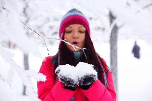 winter girl blow on snow in hands