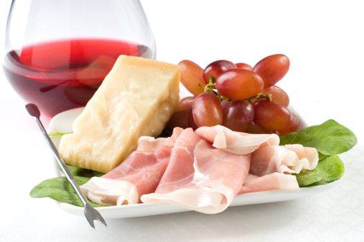 Italian appetizer plate of cheese, grapes and ham.