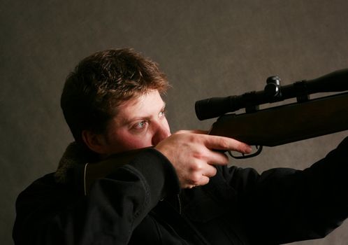 The man with the weapon in studio on a dark background