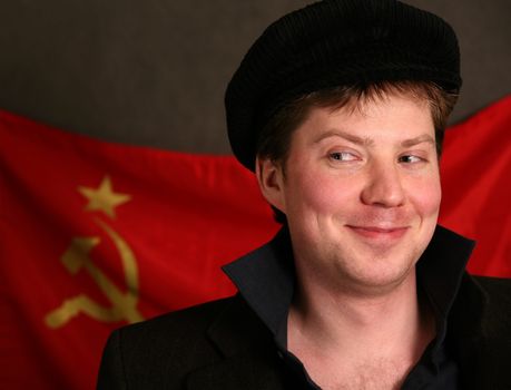 Portrait of the man in a cap on a background of a red flag