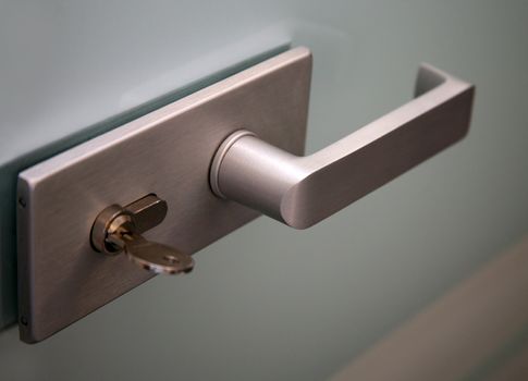 Metal door handle and the lock on a glass door