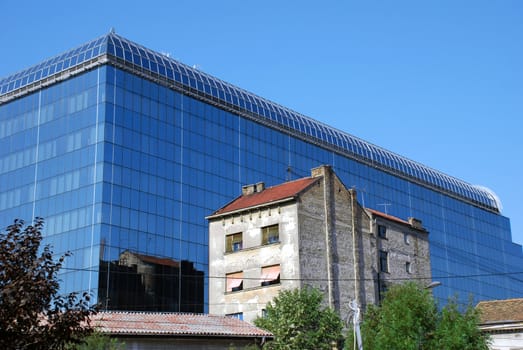 modern new glass building by old brick house in Belgrade