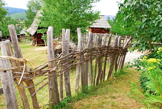 Ethnic Serbia, wooden house behind fence over rural landscape