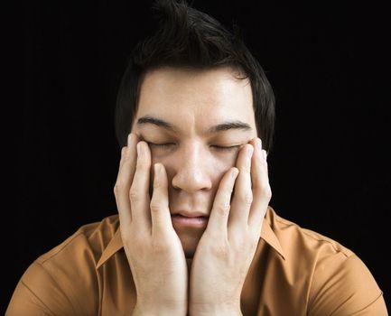 Portrait of Asian young man with hands on face.