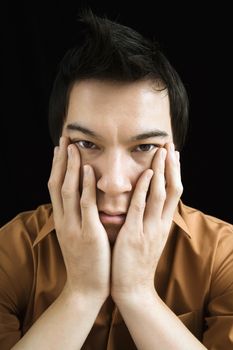 Portrait of Asian young man with hands on face.