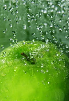 Water drops falling onto a green apple