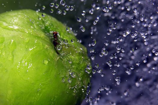 Water drops falling onto a green apple