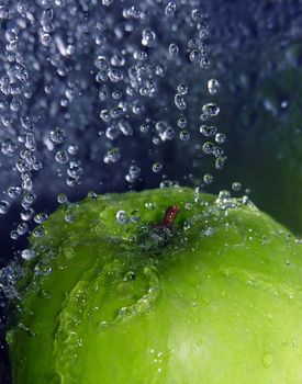 Water drops falling onto a green apple
