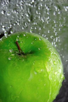 Water drops falling onto a green apple