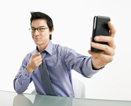 Businessman taking photograph of himself using pda or mobile phone deivice.