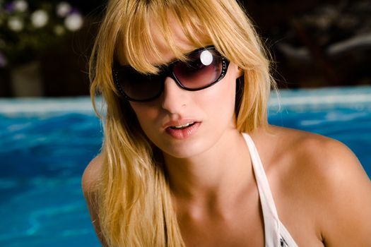 Young blond girl enjoying the sun in and around the swimming pool