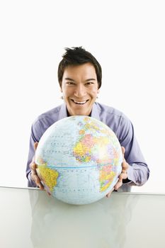 Young Asian man sitting holding globe smiling.